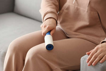 Woman cleaning clothes with lint roller, closeupの写真素材