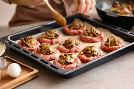 Woman mushrooms into minced meat putting boat at table