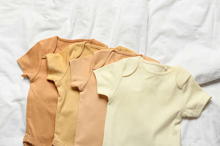 Different baby clothes on bed