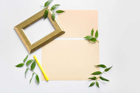 Composition with blank cards, empty picture frame, pen and leaves on white background