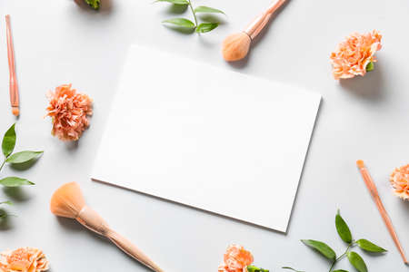 Composition with blank paper sheet, makeup brushes and flowers on light backgroundの写真素材