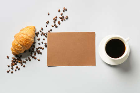 Composition with blank card, cup of coffee, croissant and coffee beans on gray backgroundの写真素材