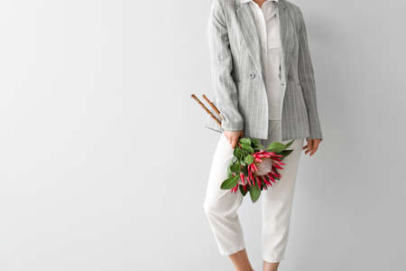 Beautiful young woman with protea flowers on light backgroundの写真素材