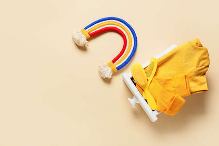 Drawer with baby clothes, toy, hair comb and brush on color background