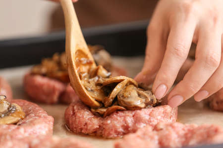 Woman mushrooms into minced meat putting boat at tableの写真素材