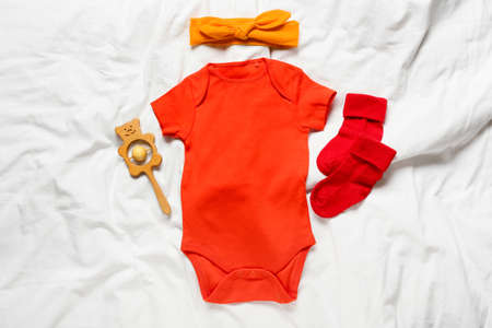 Baby clothes, headband and toy on bedの写真素材