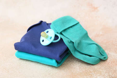 Baby clothes, socks and pacifier on grunge background