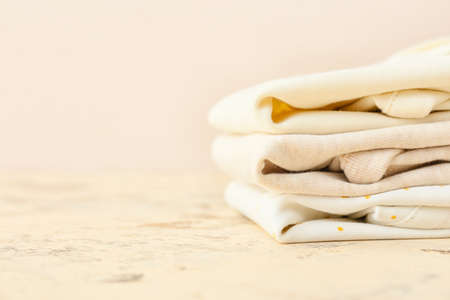 Stack of baby clothes on color background