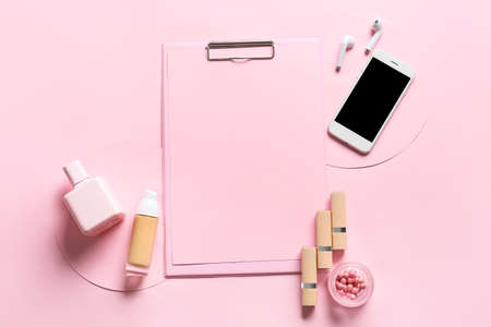 Composition with blank sheet of paper, mobile phone, earphones and cosmetics on color backgroundの写真素材