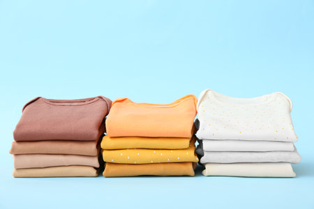 Stacks of baby clothes on color backgroundの写真素材