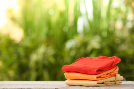 Stack of baby clothes on wooden table outdoorsの写真素材