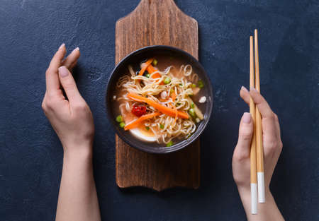 Woman eating tasty Chinese soup on dark backgroundの写真素材