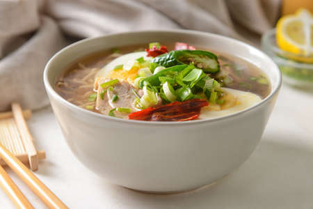 Tasty Chinese soup with chicken in bowl on light background, closeup