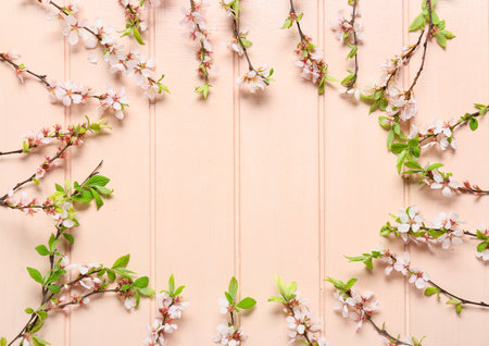 Frame made of beautiful blooming branches on color wooden background