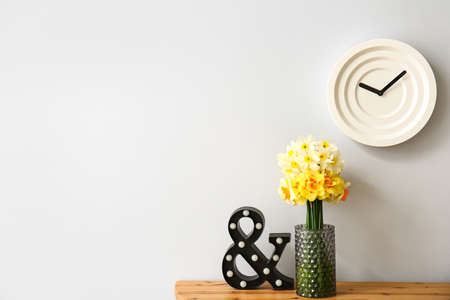 Vase with narcissus flowers on table in room