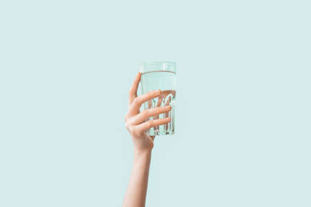 Female hand with glass of water on color background