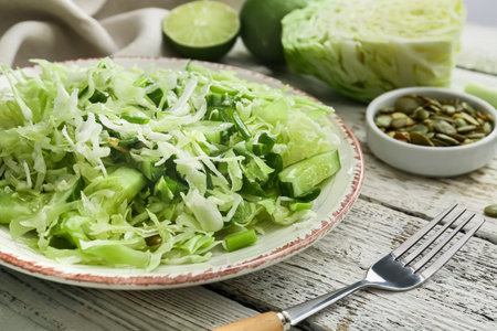 Plate with tasty cabbage salad on light wooden tableの写真素材