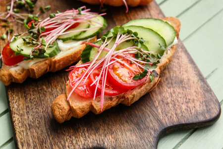 Tasty croissants with vegetables and micro green on color wooden background, closeupの写真素材