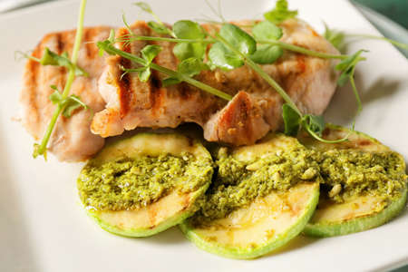 Plate with tasty grilled chicken meat, zucchini and pesto sauce, closeupの写真素材