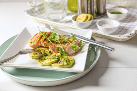 Plate with tasty grilled chicken meat, zucchini and pesto sauce on light wooden background, closeupの写真素材
