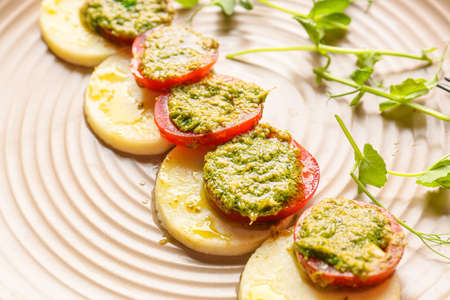 Mozzarella cheese with tomatoes and pesto sauce on plate, closeupの写真素材