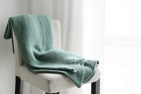 Chair with knitted plaid near window