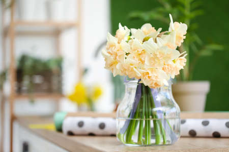 Vase with narcissus flowers on table in flower workshopの写真素材