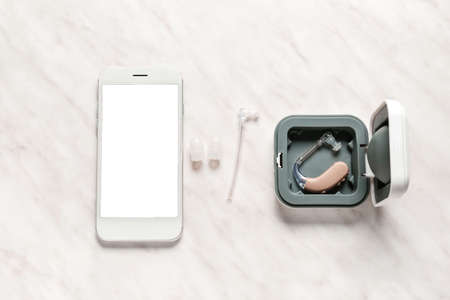 Mobile phone with hearing aid and accessories on white background