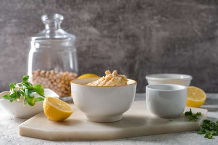 Bowl with tasty hummus and lemon on tableの写真素材