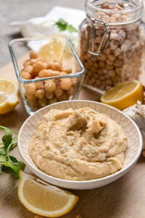 Bowl with tasty hummus and ingredients on tableの写真素材