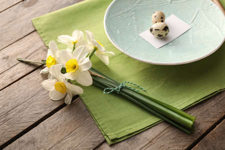 Beautiful table setting with narcissus flowers and quail eggs on wooden background