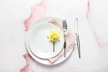 Beautiful table setting with narcissus flower on color background