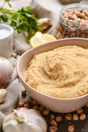 Bowl with tasty hummus and ingredients on tableの写真素材