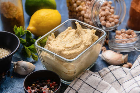 Bowl with tasty hummus and ingredients on color background