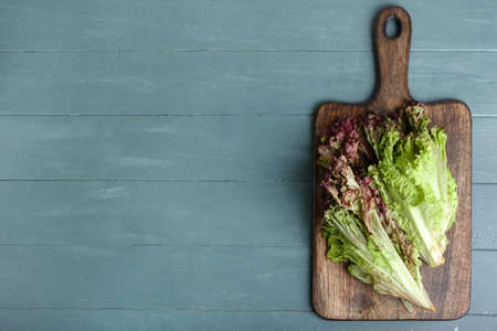 Board with fresh Lollo Rosso lettuce on color wooden backgroundの写真素材