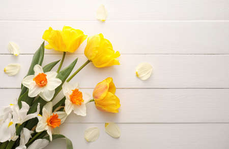 Beautiful flowers on light wooden background