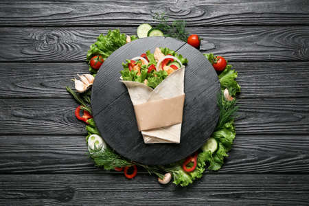 Board with tasty doner kebab and vegetables on dark wooden backgroundの写真素材