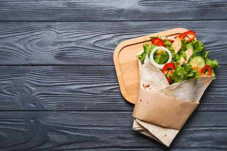 Board with tasty doner kebab on dark wooden background