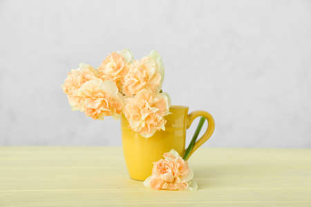 Cup with beautiful narcissus flowers on color backgroundの写真素材