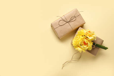 Gift boxes and bouquet of beautiful narcissus flowers on color background