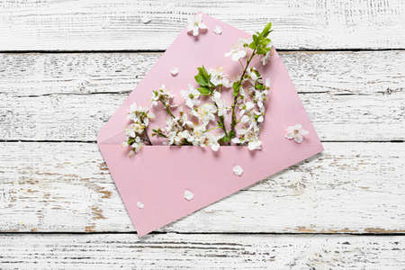 Beautiful blooming branches and envelope on light wooden backgroundの写真素材