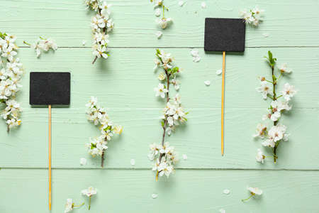 Beautiful blooming branches and price tags on color wooden background