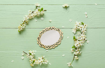 Beautiful blooming branches and blank card on color wooden background