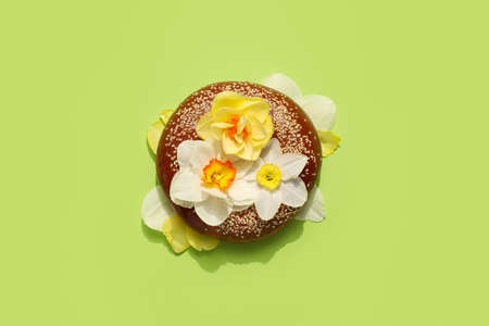 Tasty bagel and beautiful narcissus flowers on color background