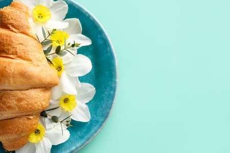 Tasty croissant with beautiful flowers on color background, closeupの写真素材