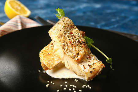 Plate with tasty baked cod fillet, greens and sauce on color background, closeupの写真素材