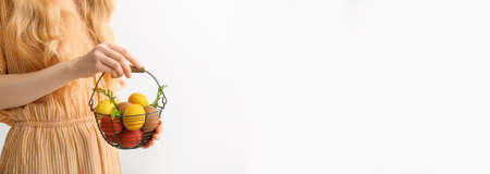 Woman holding basket with painted Easter eggs on white background with space for textの写真素材