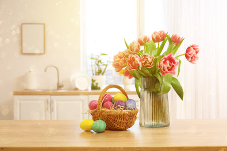 Basket with Easter eggs and vase with tulips on table in kitchenの写真素材