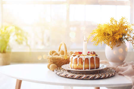 Easter cake with eggs in basket and mimosa flowers on tableの写真素材