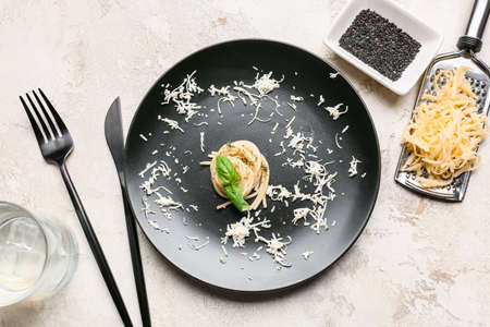 Plate with tasty pasta and cheese on light background